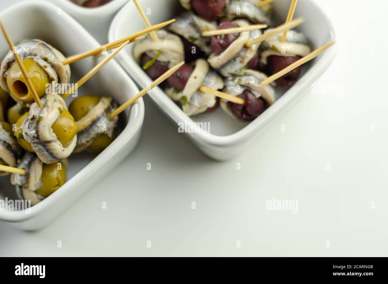 The traditional Spanish appetizers of olives, tomatoes and anchovies in a white ceramic bowls