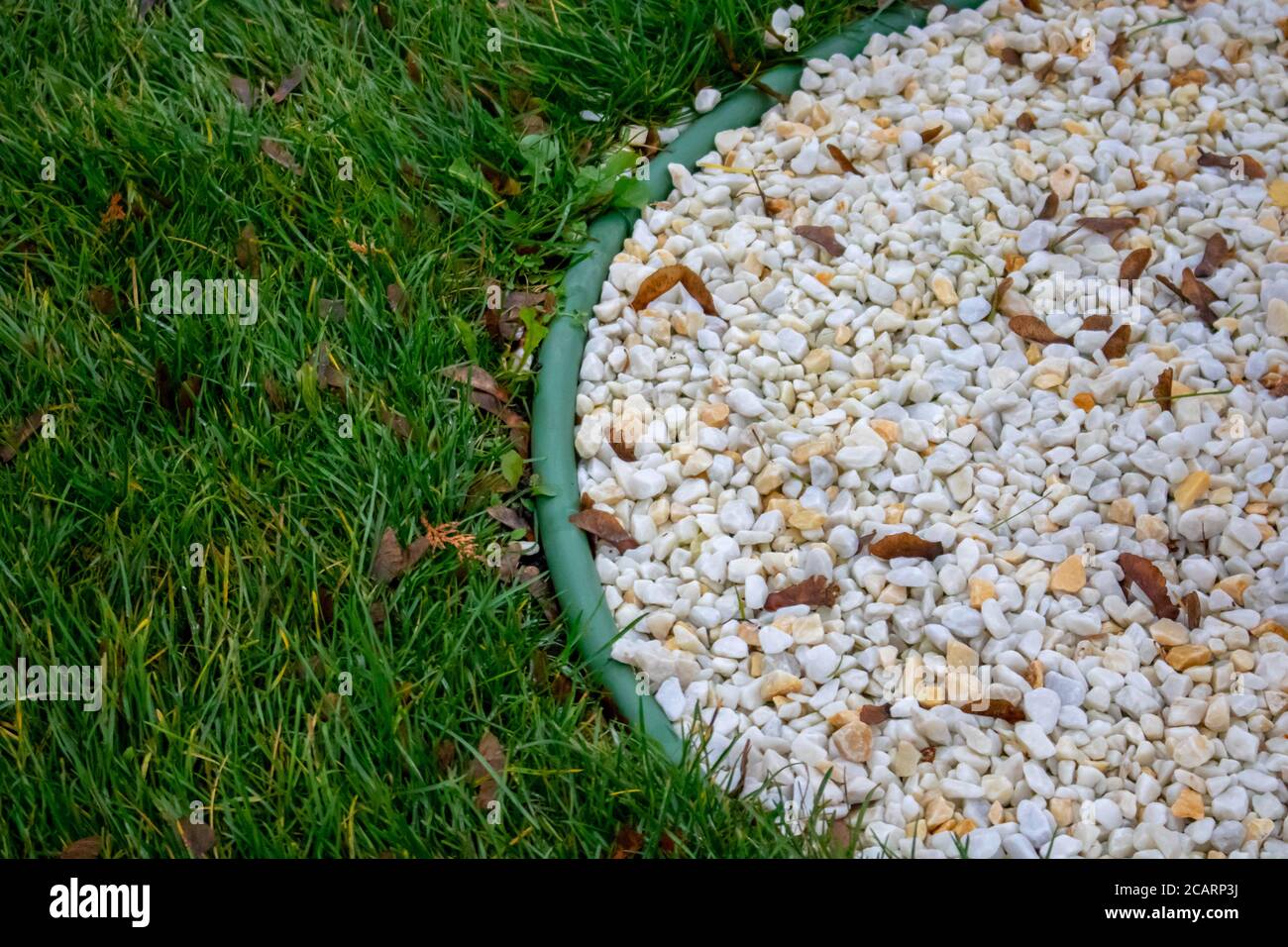 Decorative ground in the garden with artificial grass, gravel and