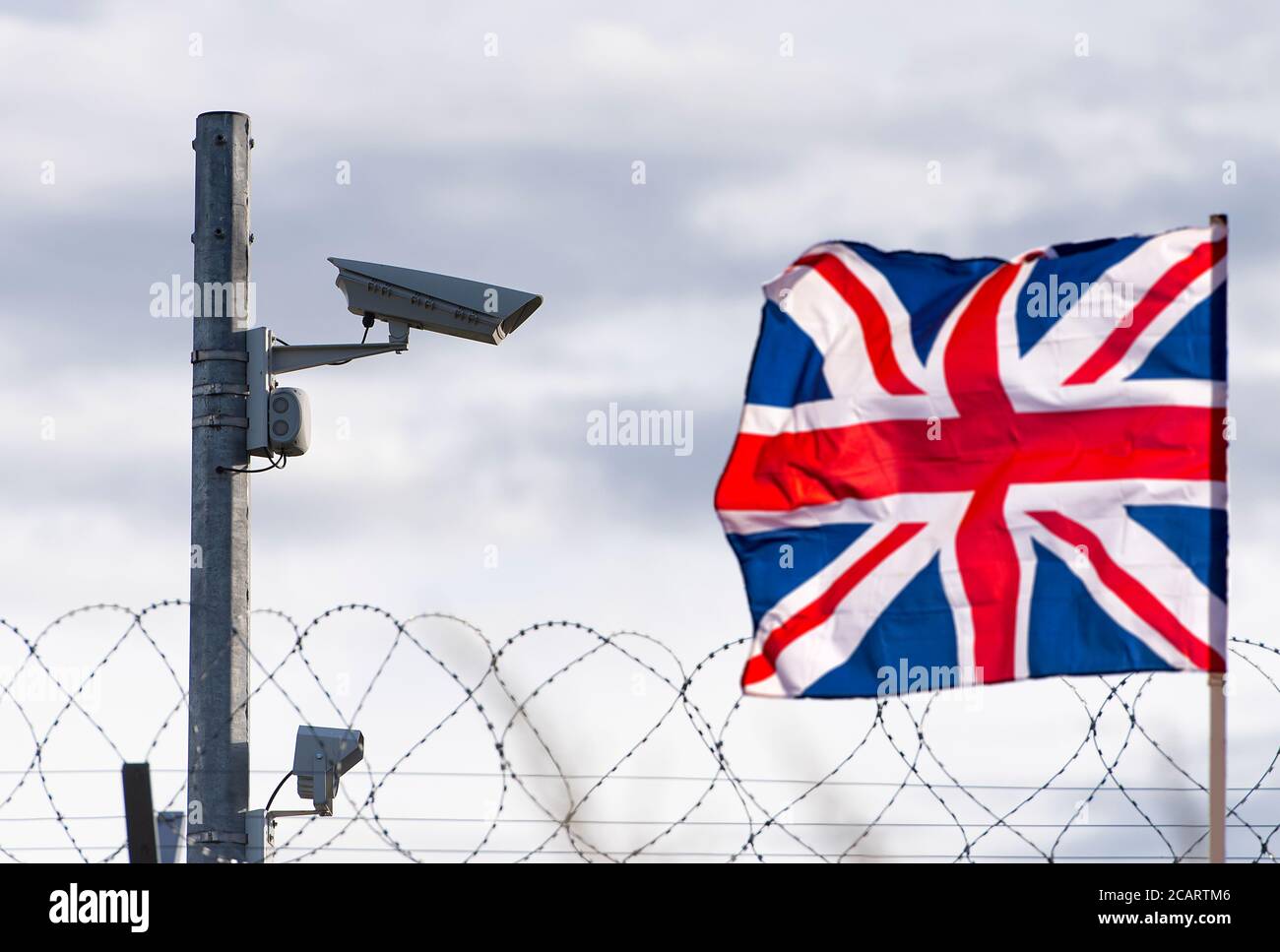 Flag of the United Kingdom with surveillance camera and barbed wire, concept picture Stock Photo
