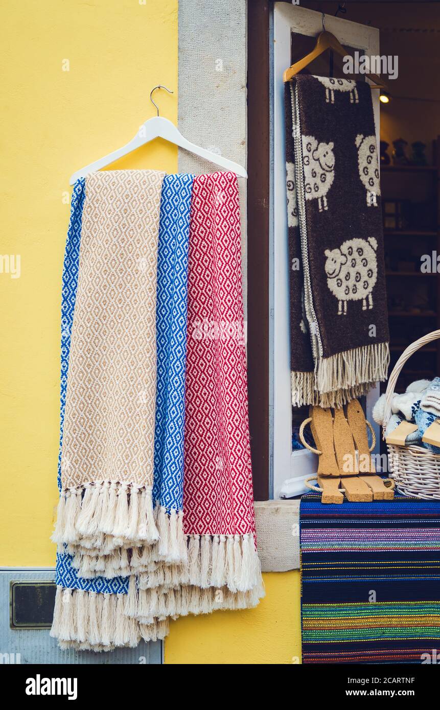 many traditional portuguese wool scarves and cotton cloth with different colors hanging from a window Stock Photo