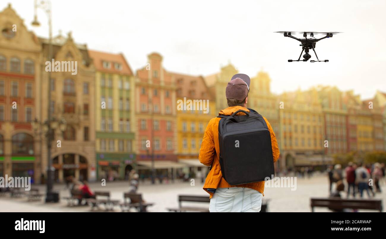 A man with a backpack controls a drone on a background of a European city Stock Photo