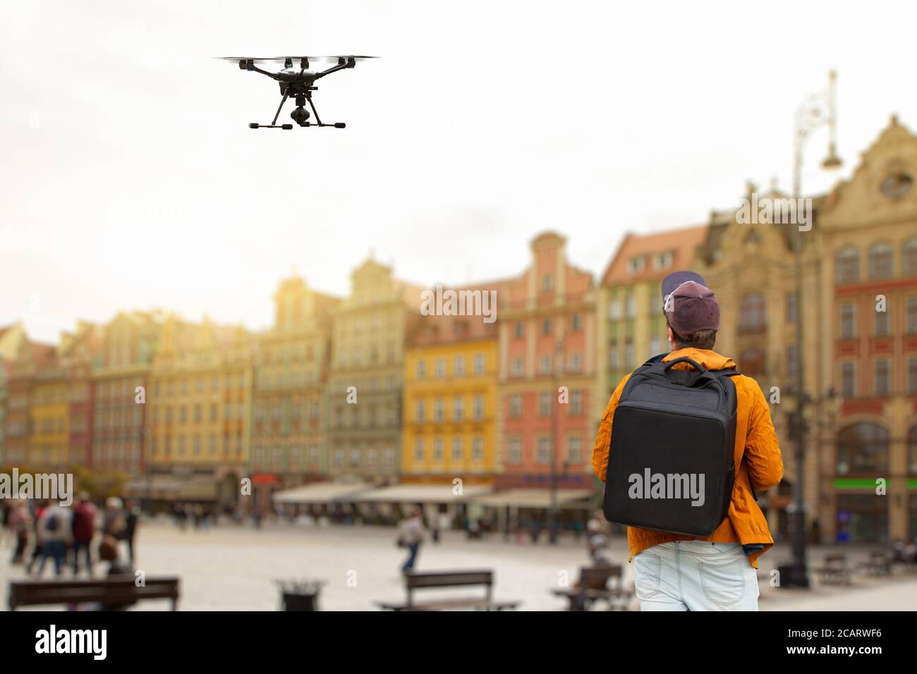 A man with a backpack controls a drone on a background of a European city Stock Photo