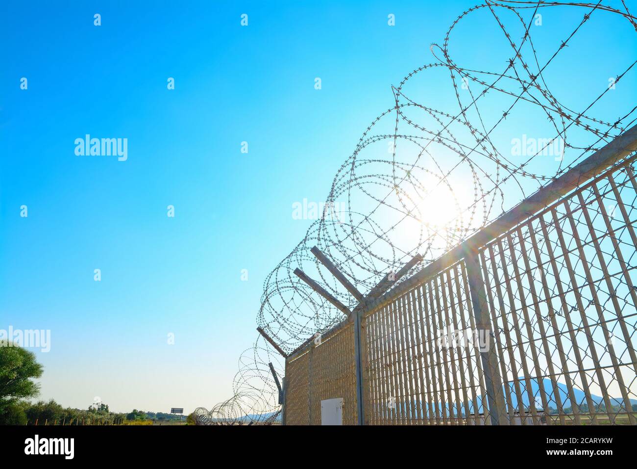 metal fence with barbwire under a bright sun Stock Photo - Alamy