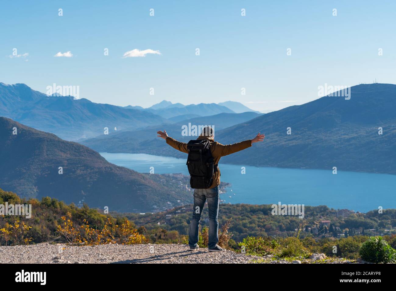 A traveler with a backpack stands on the top of the mountain Stock Photo
