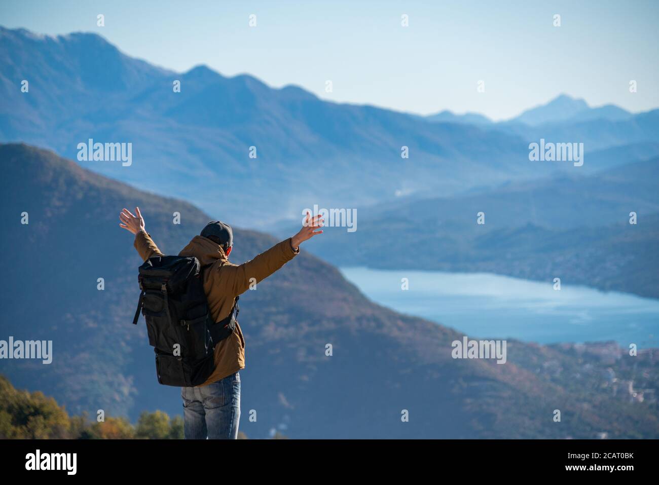 A traveler with a backpack stands on the top of the mountain Stock Photo
