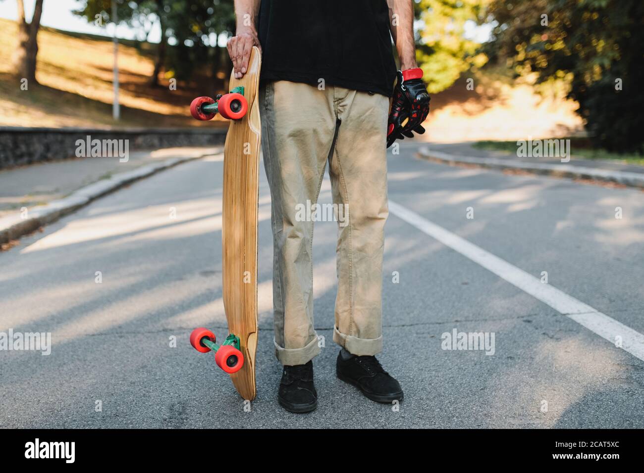 The guy is holding a board with red wheels. Skateboarding in the