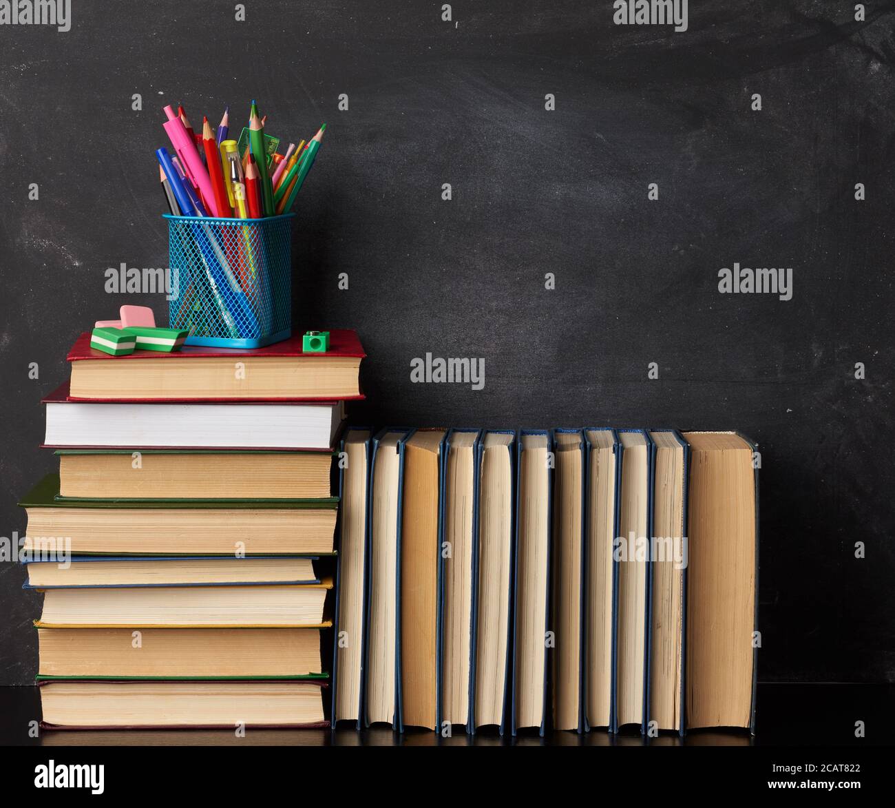 stack of various books, stationery on black chalk board background, back to school, copy space