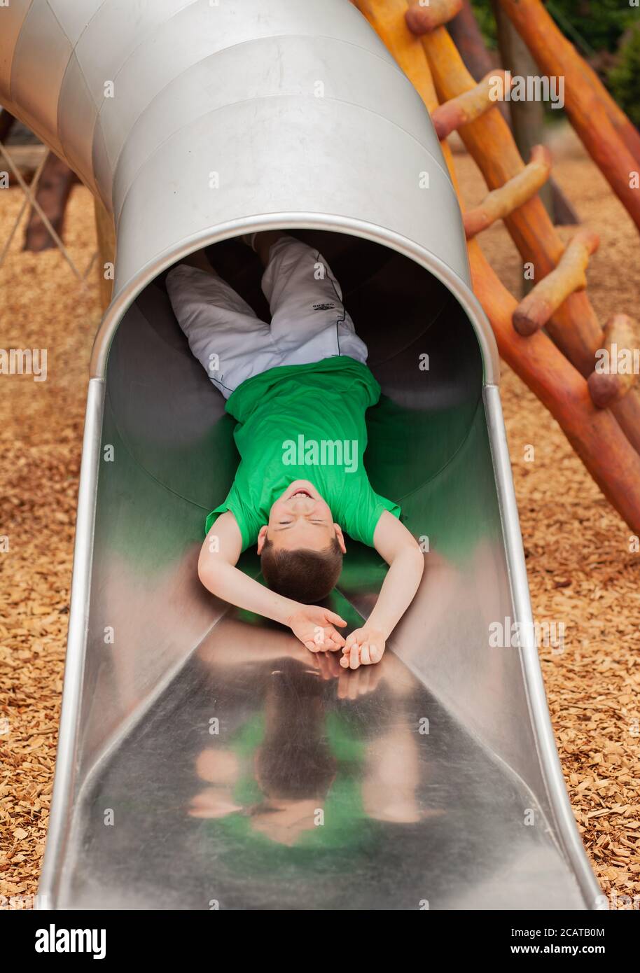 Young Boy Playing On a Slide in a Park Stock Photo