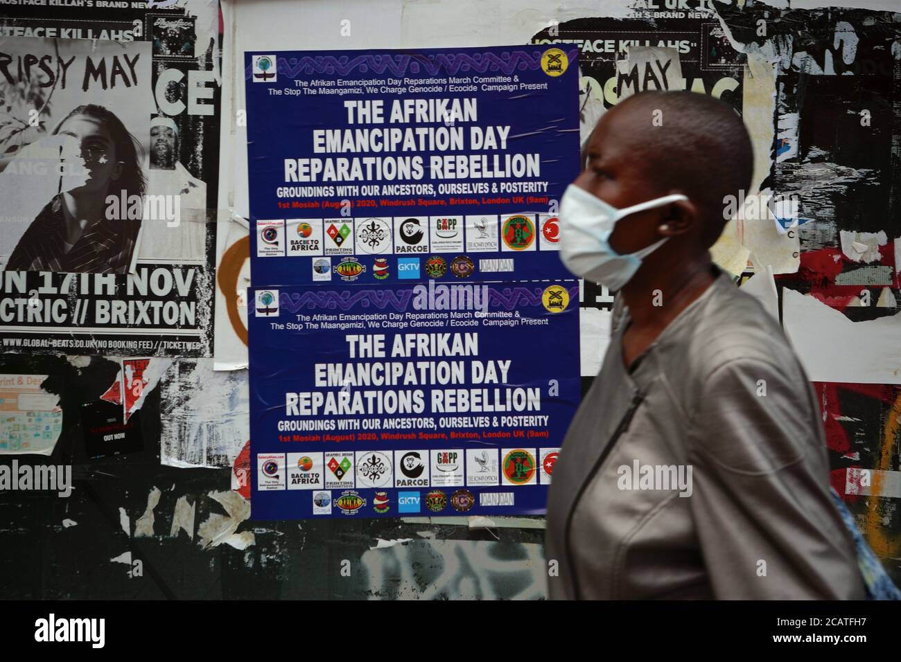 Peckham   London (UK), August 2020: A woman wearing a face covering walks past a poster advertising 'Afrikan Emancipation Day' in SE London. Emancipat Stock Photo