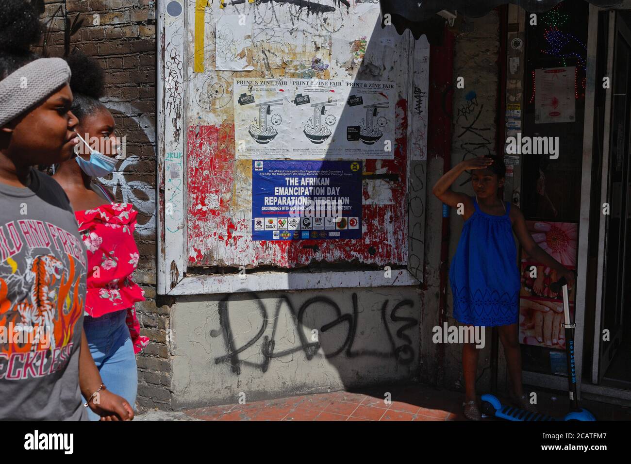Peckham   London (UK), August 2020: Women walk past a poster advertising 'Afrikan Emancipation Day' in SE London. Emancipation day is held yearly on t Stock Photo