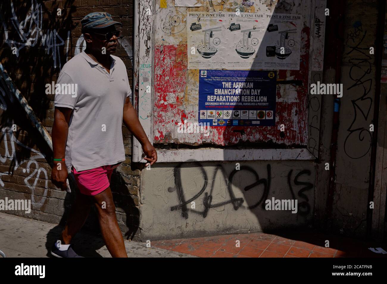Peckham   London (UK), August 2020: A man walks past a poster advertising 'Afrikan Emancipation Day' in SE London. Emancipation day is held yearly on Stock Photo