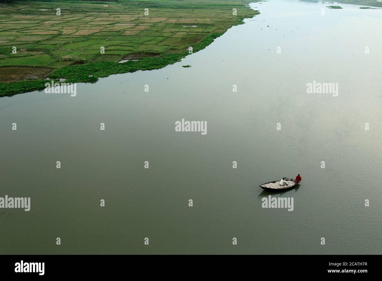 Top view of the river, towing boat pulls the barge with wooden materials in the summer evening. Aerial view of the landscape from the air. Stock Photo