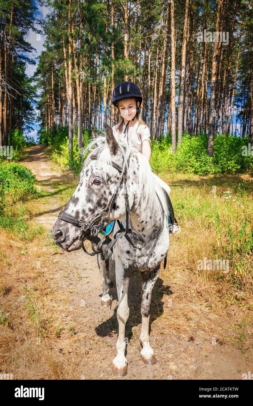 cute girl on a white horse with black spots Stock Photo