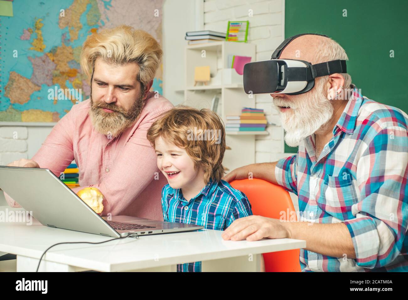 Three generations of men having fun together. GrandFather, father and son playing computer games at home. Parenting childhood values weekend. Stock Photo