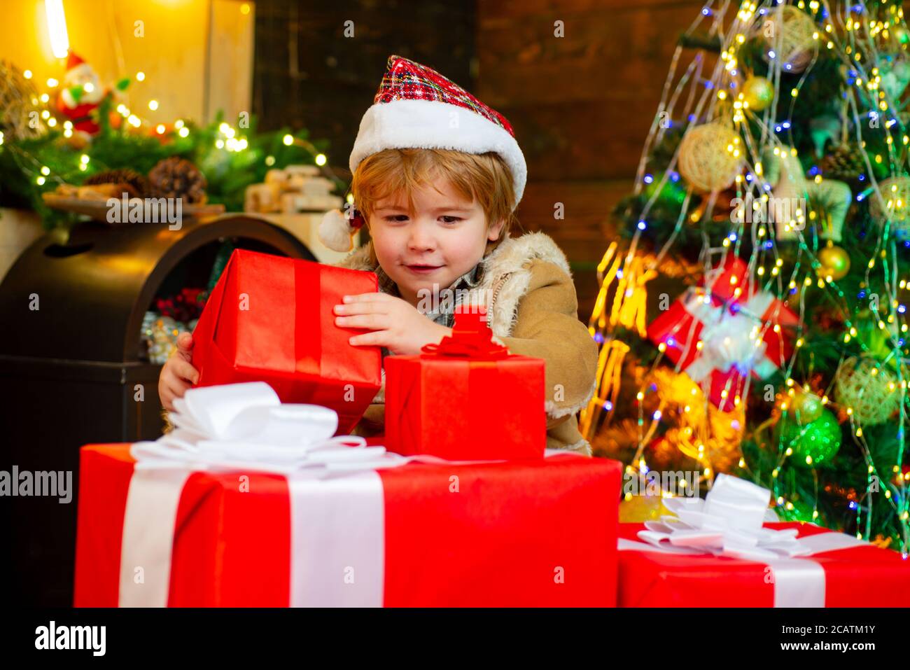 Cute little child is decorating the Christmas tree indoors. Cute little ...