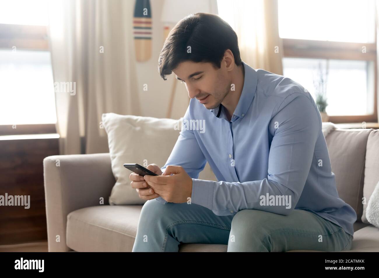 Pleased young handsome happy guy using smartphone. Stock Photo