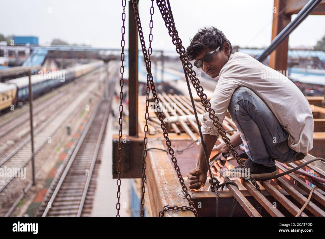 Agra / India - February 22, 2020: indian man welding irons on overpass of train station Stock Photo