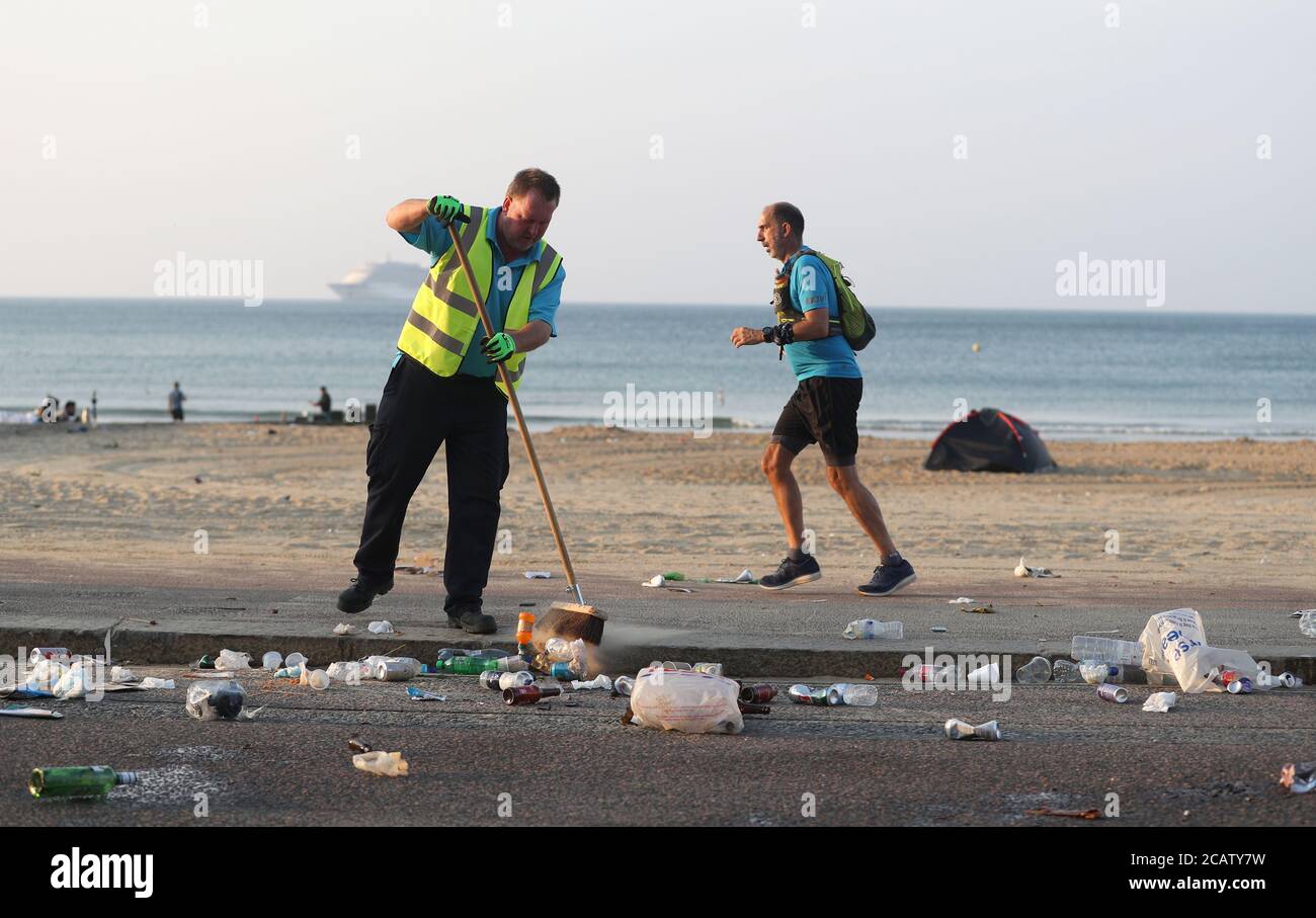 A member of BCP council sweeps up excess waste that fell from bins that were emptied on