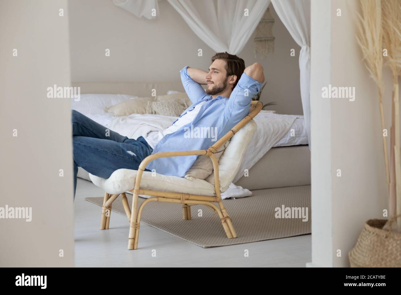 Satisfied calm young man relaxing stretching on cozy chair Stock Photo