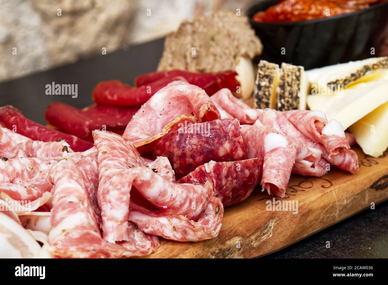 Rustic Tuscan tray with typical products: prosciutto (ham), brawn, finocchiona, crostini, salami, tuscan chilli and sliced pecorino cheese. Stock Photo
