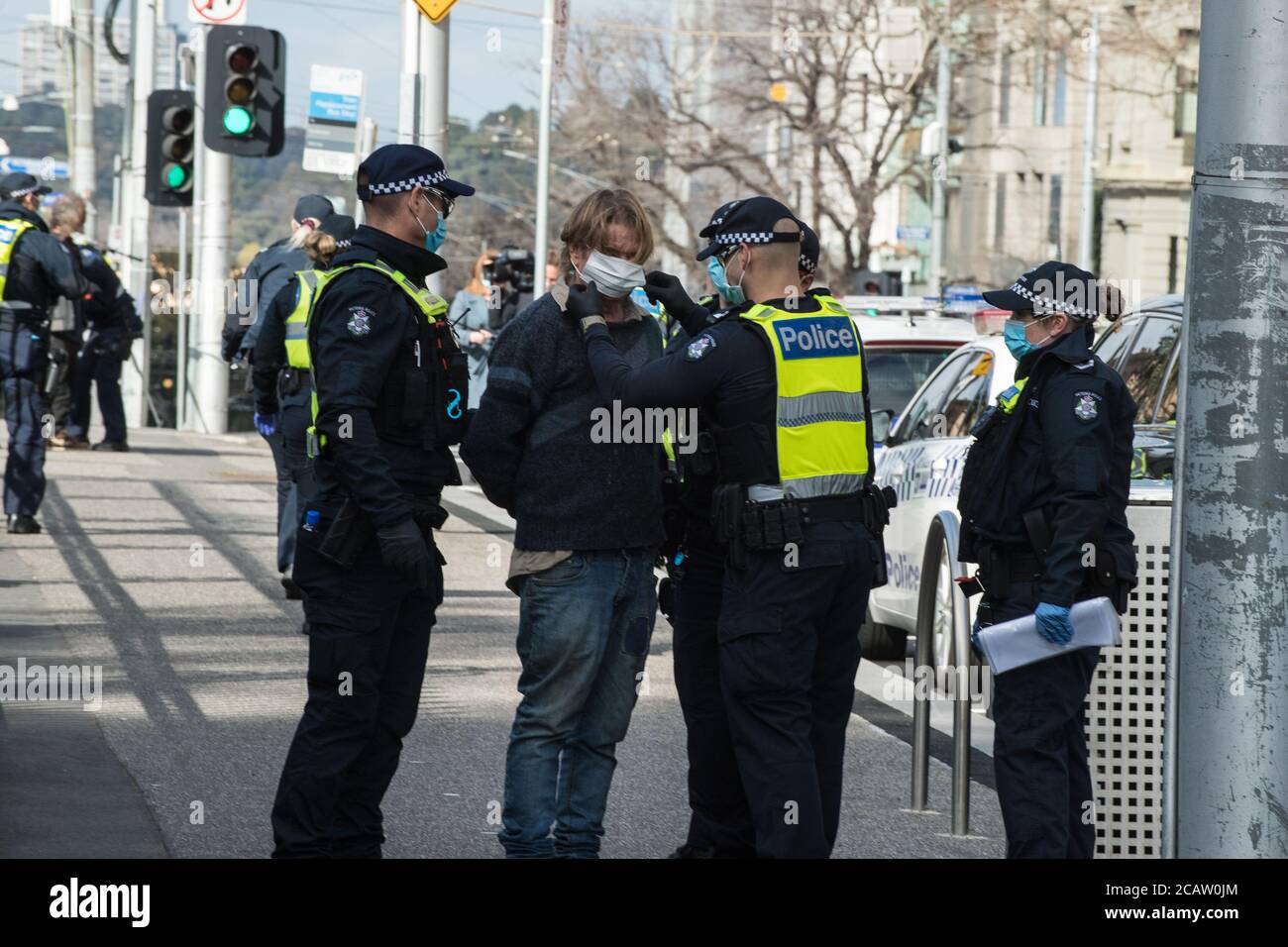 Melbourne, Australia 9 August 2020, a Victoria Police Officer fits a mask to a man who had refused to wear a mask or give his details to police, outside of the State Parliament, where an anti-mask protest was planned Credit: Michael Currie/Alamy Live News Stock Photo