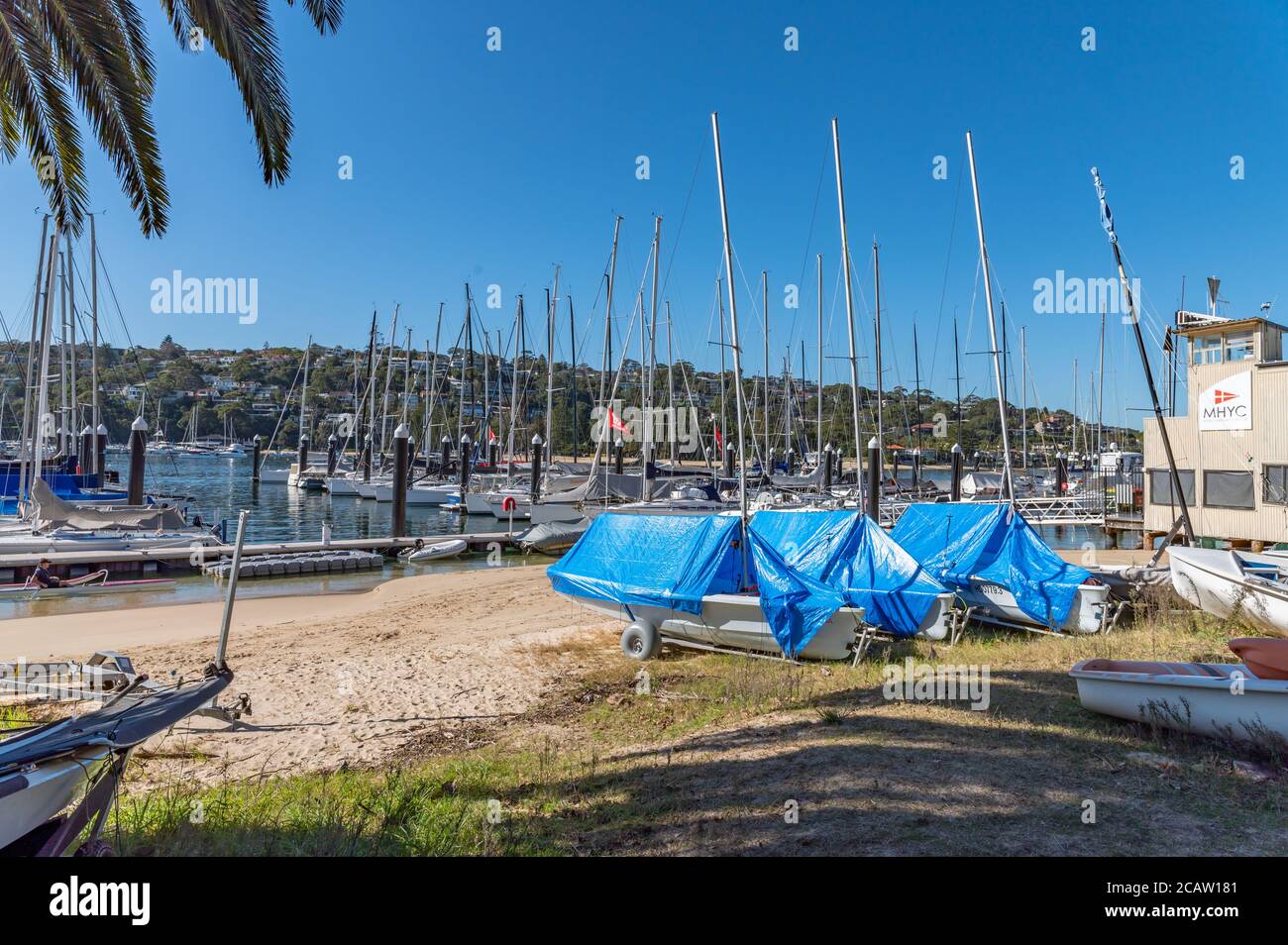 Boats covered with Tarps on the sand area in front of Middle Harbour Yacht Club on a sunny winter afternoon Stock Photo