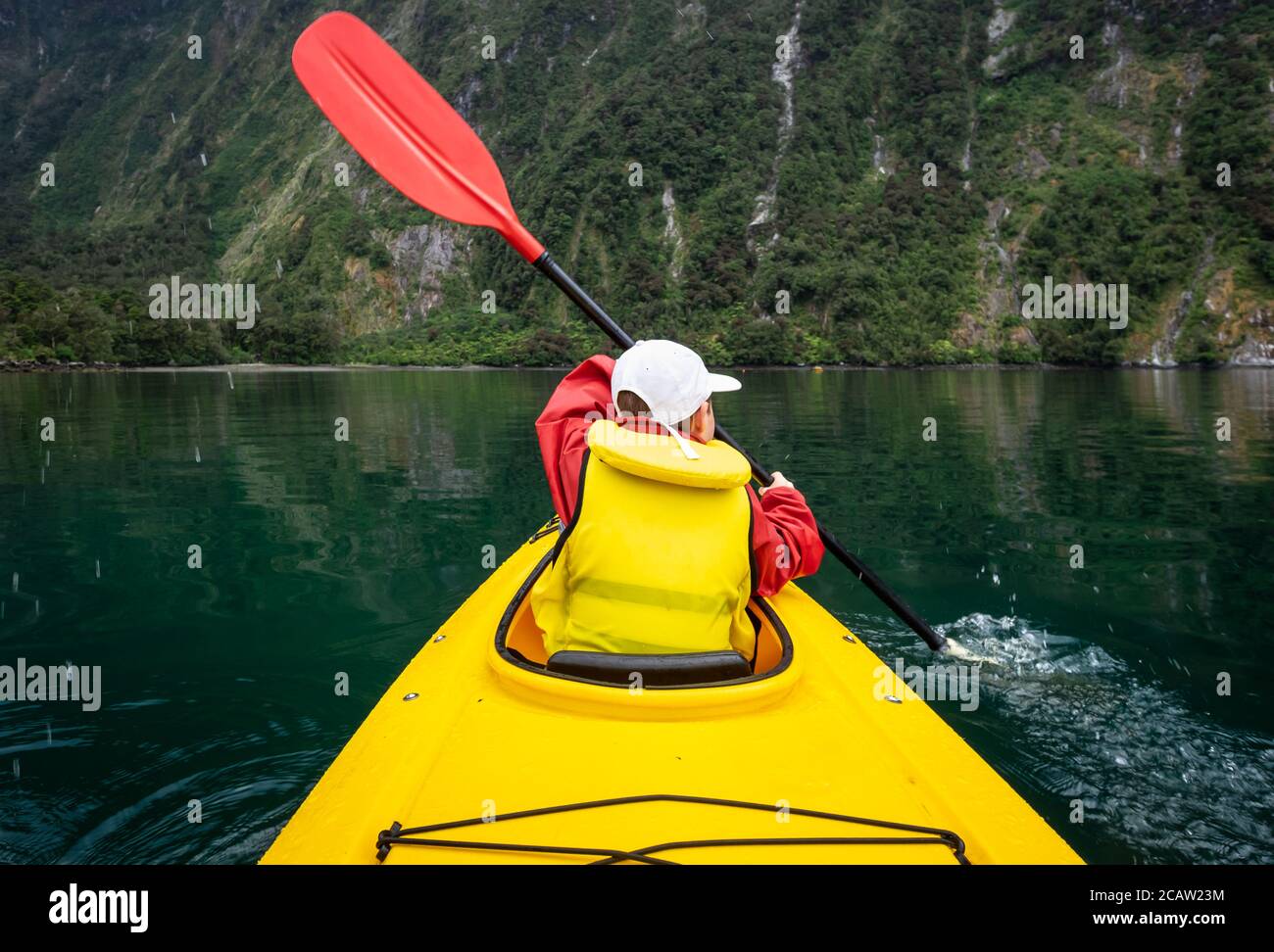Young boy in bright yellow kayak on mountain lake. Stock Photo