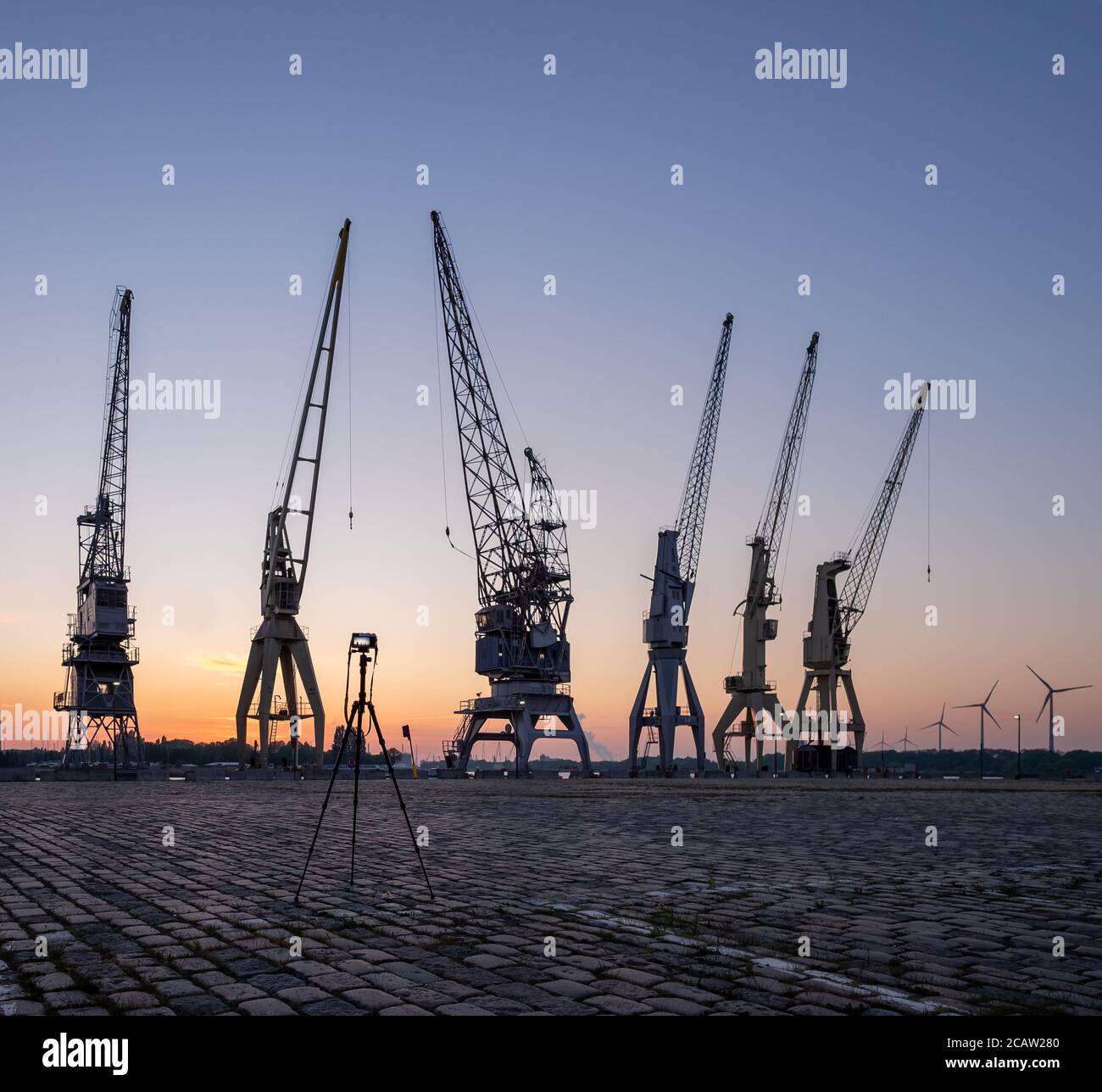 Line-up of historical cranes in the old part of the port of Antwerp with camera on tripod. Stock Photo
