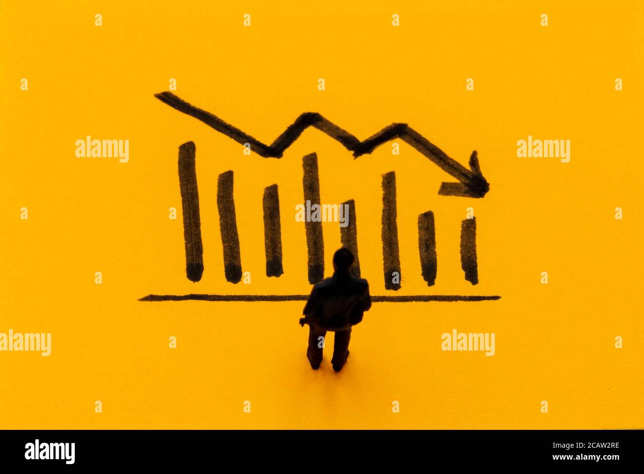 Miniature figurine posed as businessman in front of descending graph, negative performance concept image Stock Photo