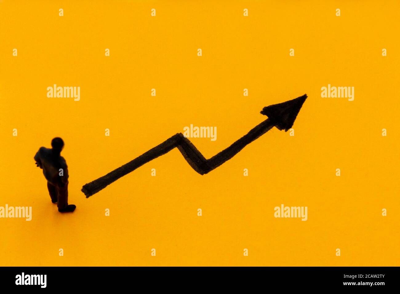 Miniature figurine posed as businessman in front of ascending graph arrow, positive performance concept image Stock Photo
