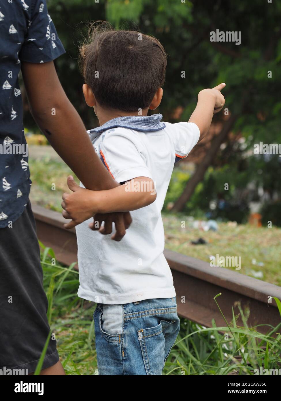 Point Out Someone Using Hand Vertical shot of a young boy pointing out something while holding ...