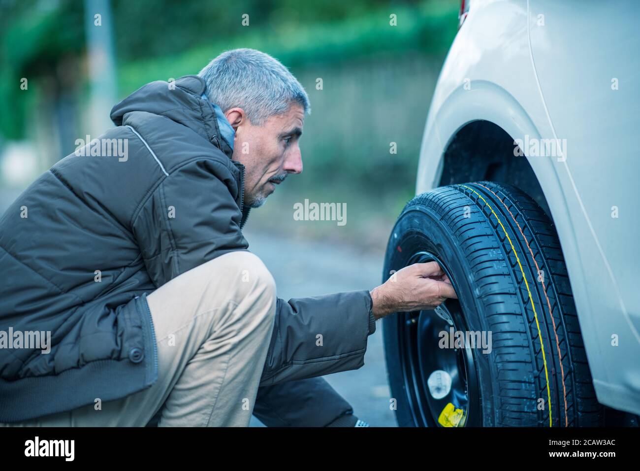 Man changing flat tire on the road. Stock Photo