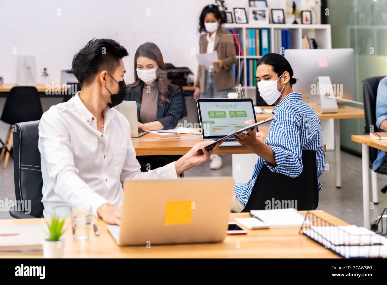 Group of interracial business worker team wear protective face mask in new normal office with social distance practice with hand sanitiser alcohol gel Stock Photo
