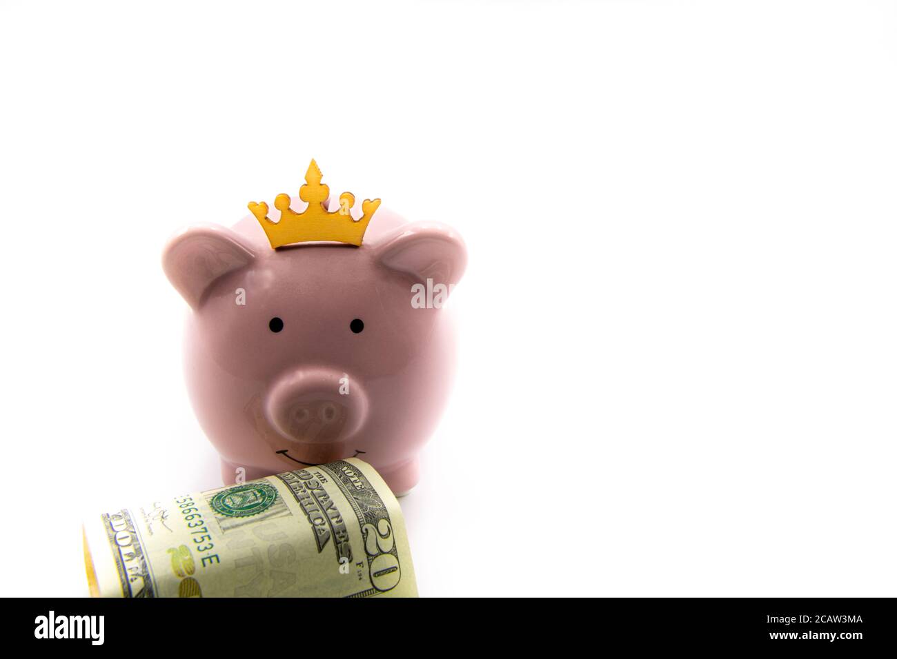 Pink piggy bank with golden crown and stack of US dollars in front isolated over white background with copy space, cash is king concept image Stock Photo