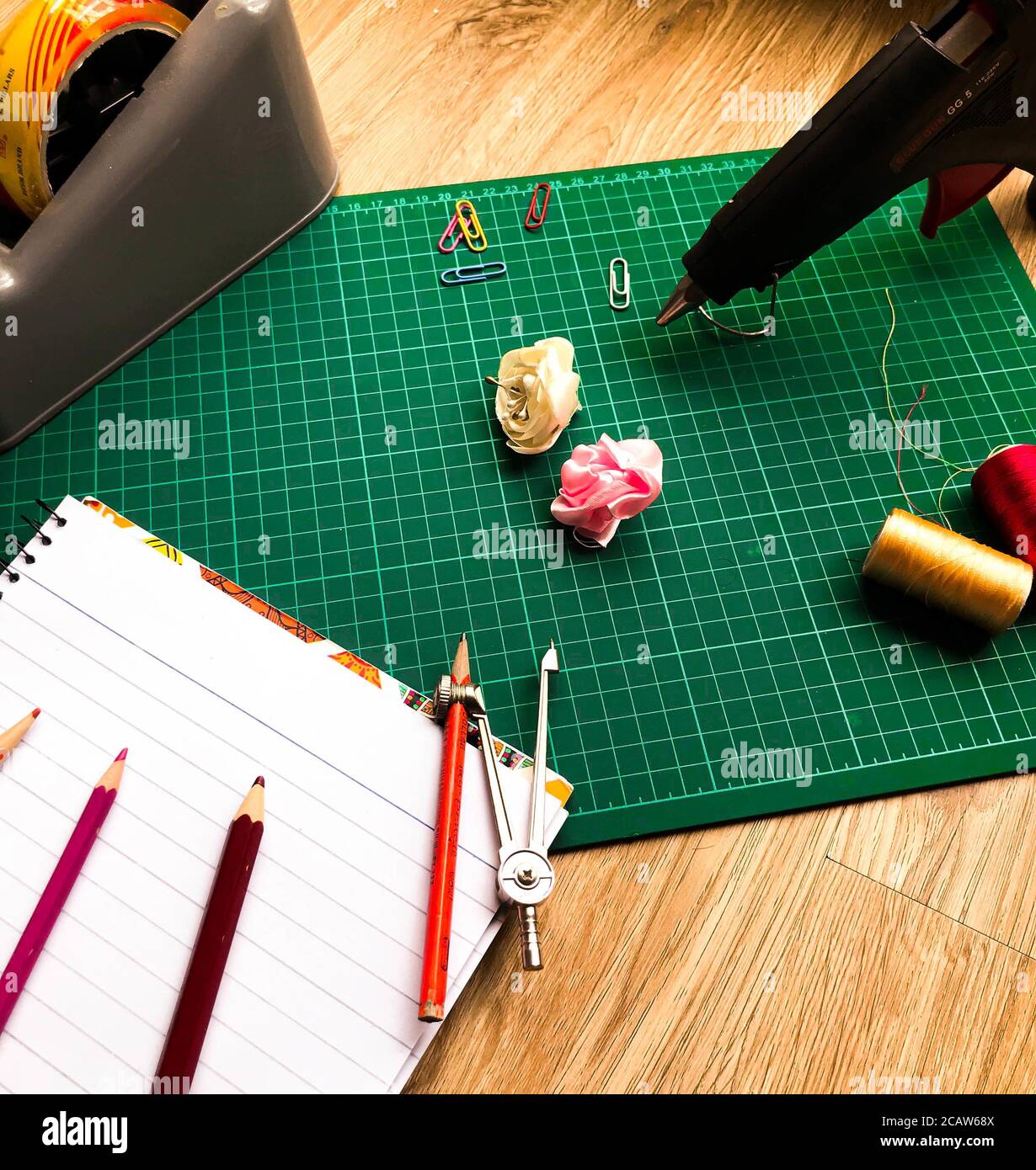High angle shot of a green gridded cutting mat with various stationery on a wooden surface Stock Photo