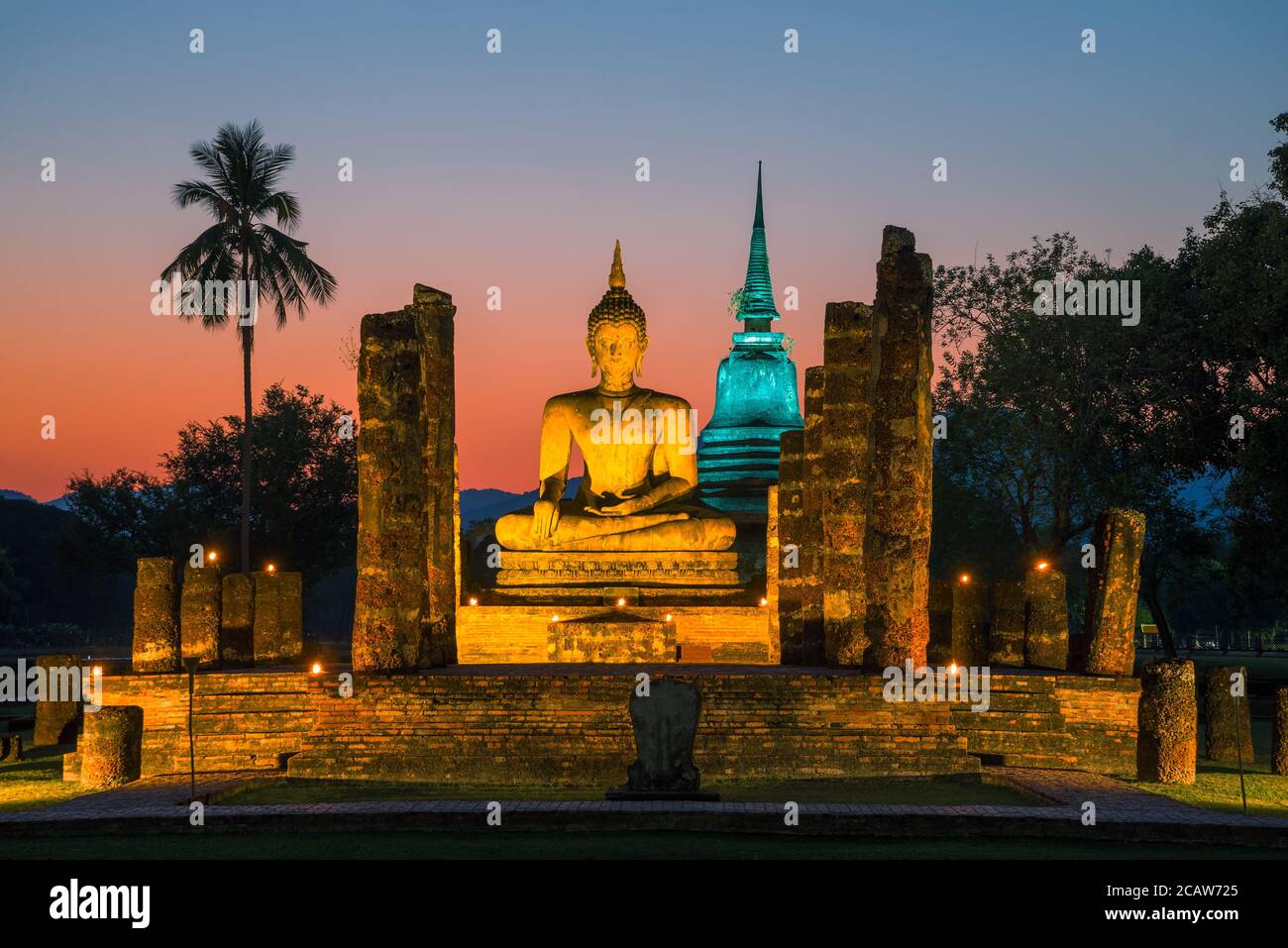 The ruins of the Buddhist temple of Wat Chana Songkhram in night lighting against the background of the outgoing sunset. Historic Park of Sukhotai Stock Photo