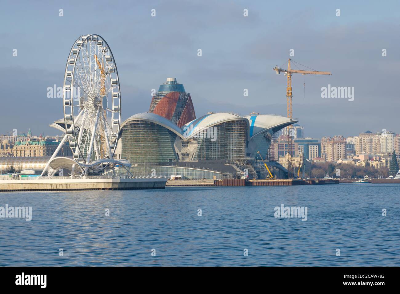 BAKU, AZERBAIJAN - DECEMBER 29, 2017: The Ferris wheel and the construction of a new shopping and entertainment center 'Caspian Waterfront Mall' again Stock Photo