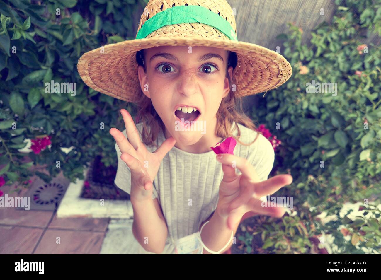 girl in a straw hat gesturing and grimacing with her face and hands Stock Photo