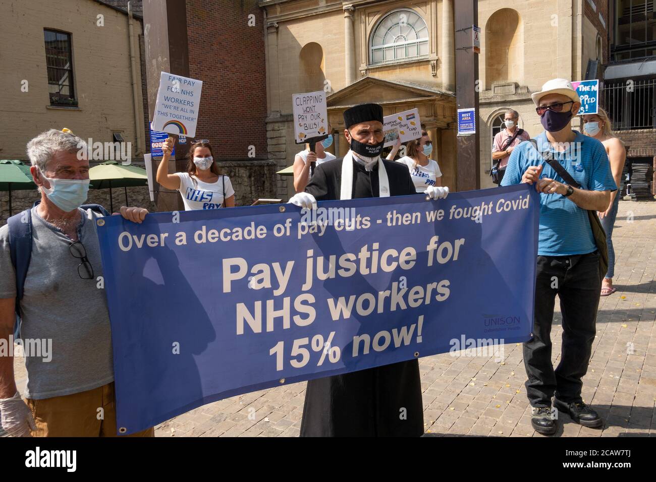 Oxford, UK. 8th August 2020. NHS workers and supporters attended a rally in Oxford’s Bonn Square calling for pay justice for all NHS workers, protesting to demand a pay rise to reflect their efforts during the covid pandemic This was one of around 38 similar rallies held throughout the UK. The protestors maintained social distancing and wore masks. While listening to speakers many held placards that highlighted their grievances and how they felt under valued. Pictured, NHS supporters  holding banner - Pay Justice For NHS Workers 15% Now! Credit: Stephen Bell/Alamy Stock Photo
