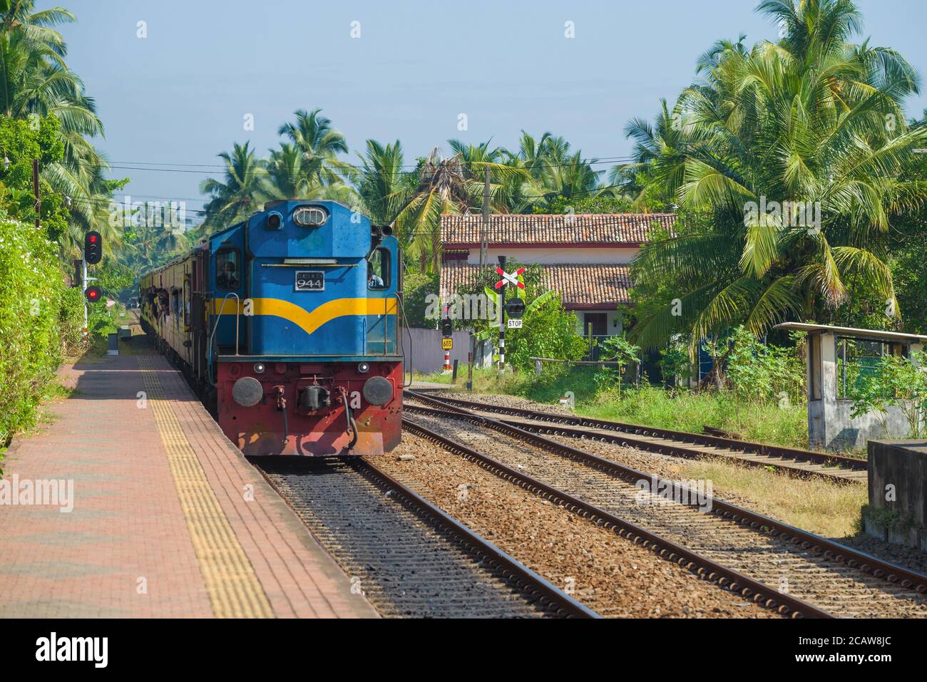 HIKKADUWA, SRI LANKA - FEBRUARY 21, 2020: A passenger train arrives on the railway station on a sunny afternoon. Stock Photo