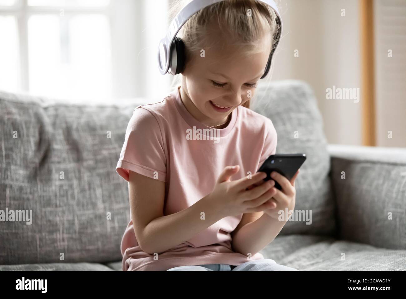 Little adorable blonde girl watching funny video on smartphone