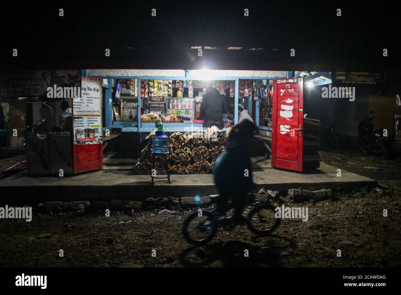 A cyclist rides past a snack shop that has reopened in Cai Rancaupas.  Kampung Cai Rancaupas