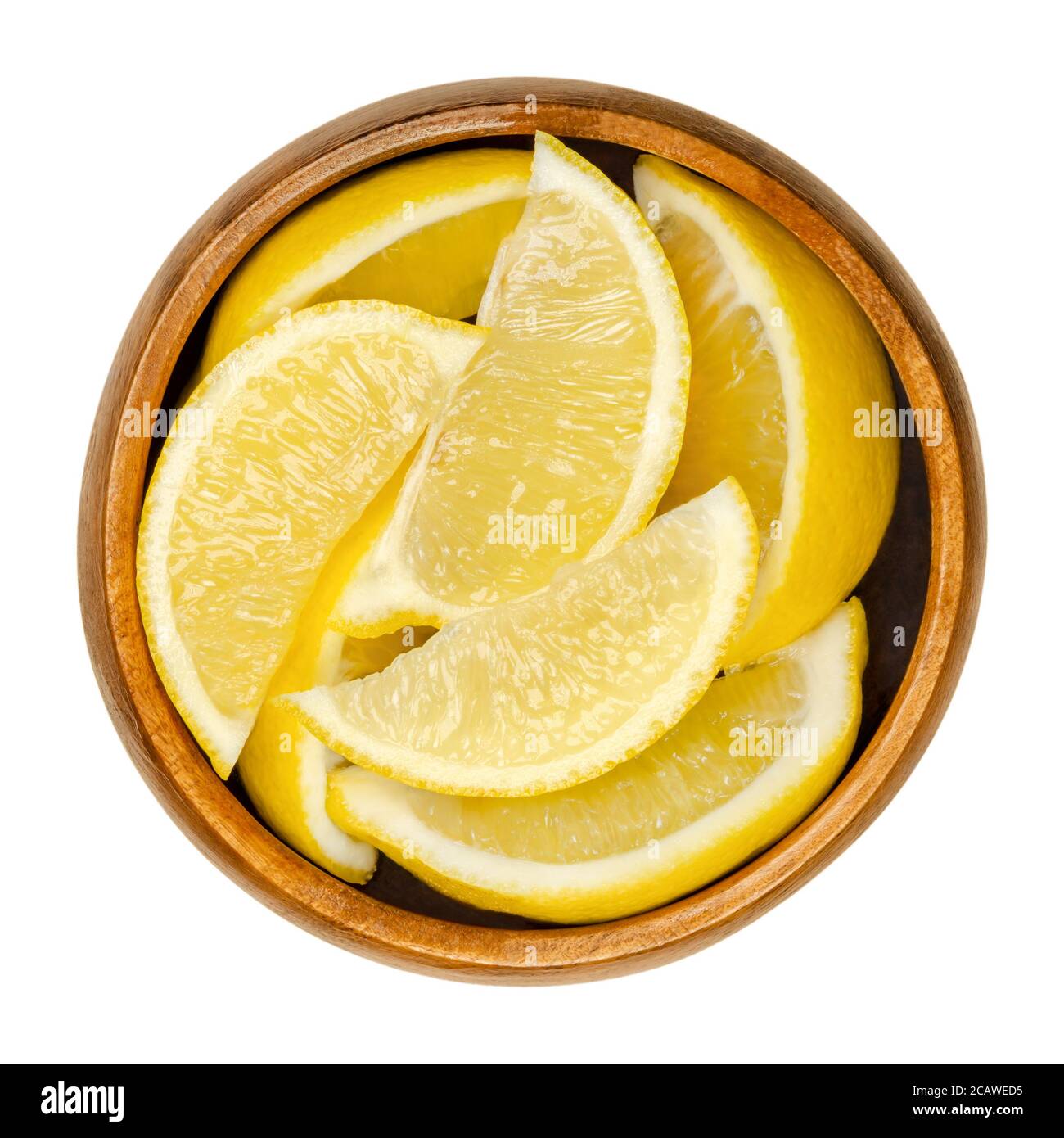 Lemon half in wooden bowl. Freshly cut ripe yellow edible citrus fruit. Citrus limon. Lemon juice is used for culinary purposes and for cleaning. Stock Photo