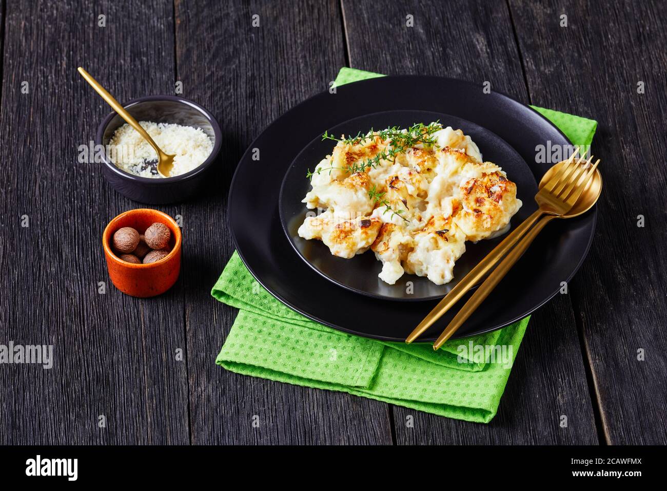Cauliflower cheese casserole served on a black plate with fresh thyme