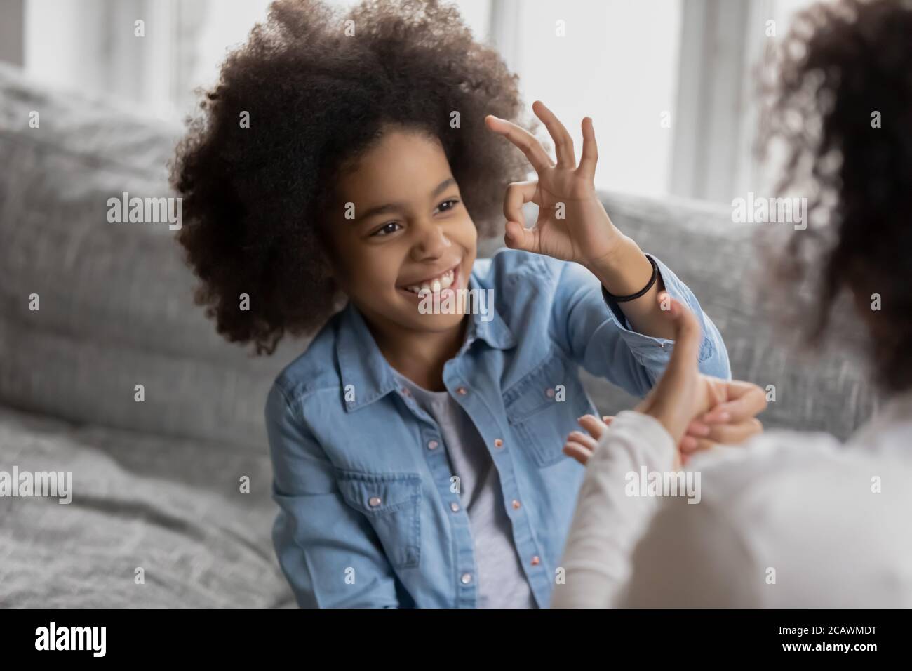 Smiling biracial girl talk sign language with mom Stock Photo