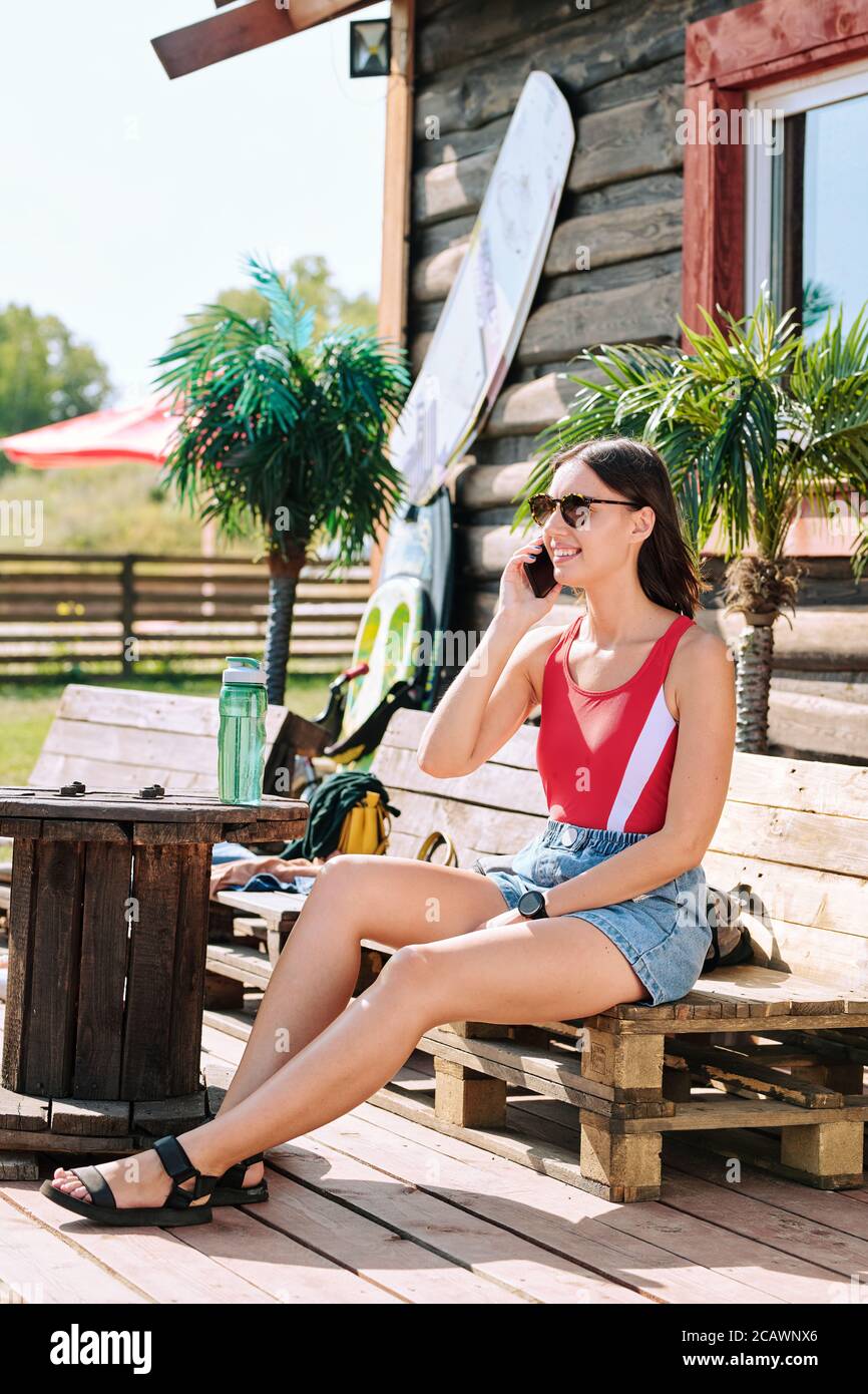 Happy young brunette female in sunglasses, red tanktop and denim shorts Stock Photo