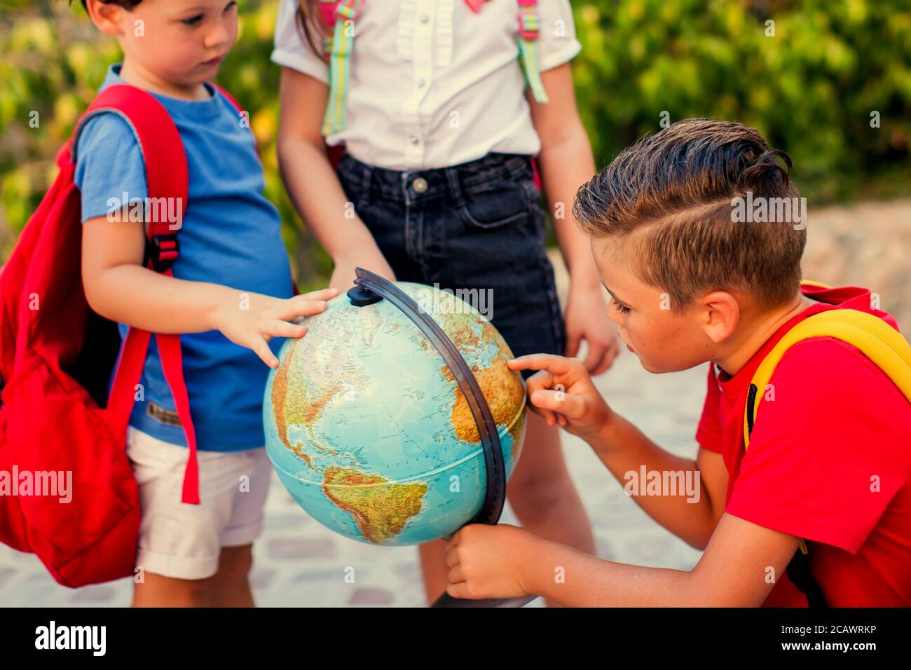 Back to school. Pupils looking at globe outdoor. Geography and