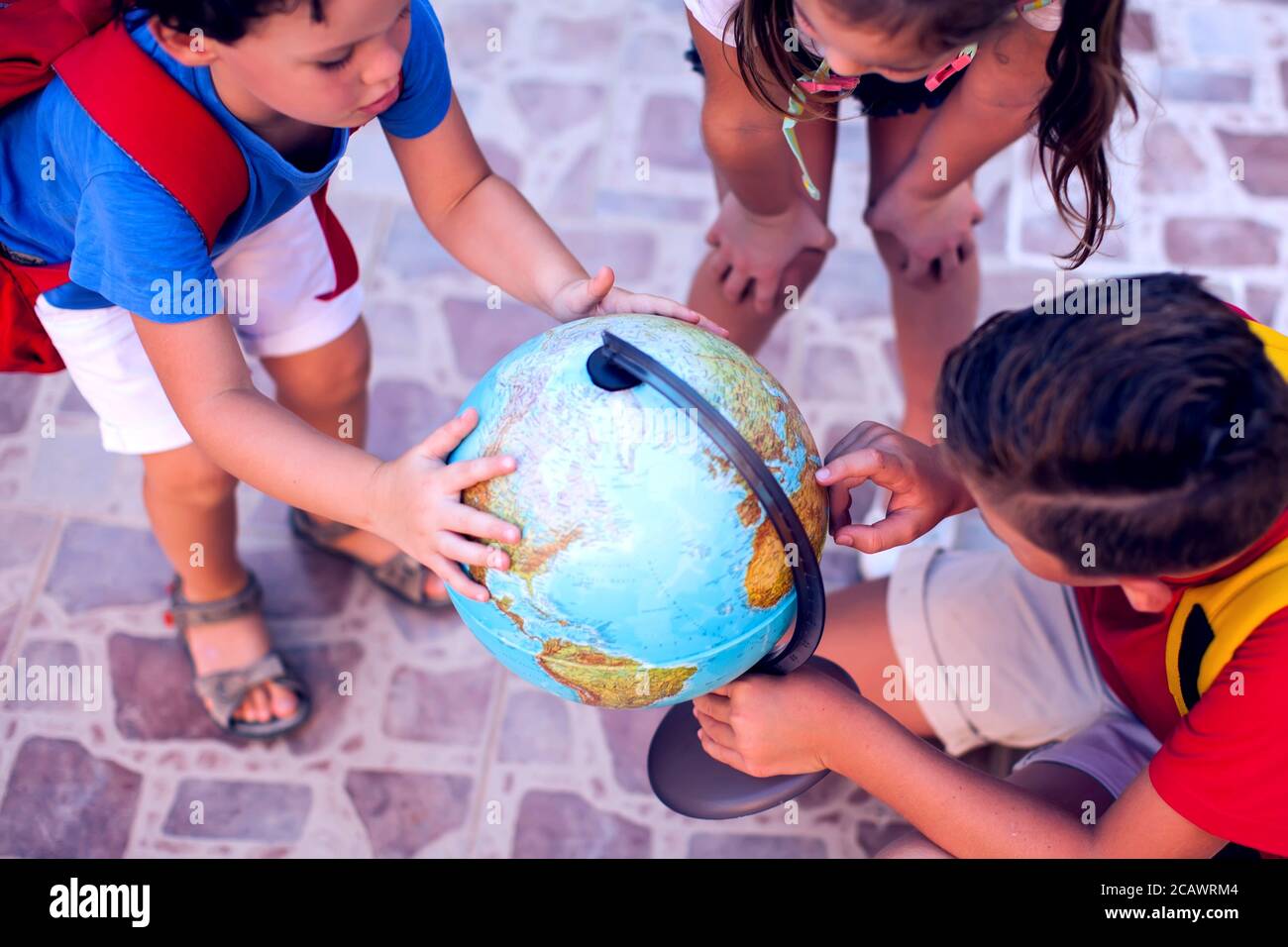 Back to school. Pupils looking at globe outdoor. Geography and