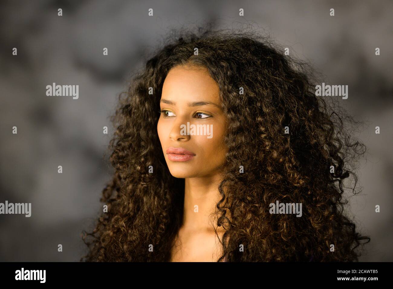 Headshot of a beautiful thoughtful black girl with long curly hair looking off to the side with a pensive serious expression Stock Photo