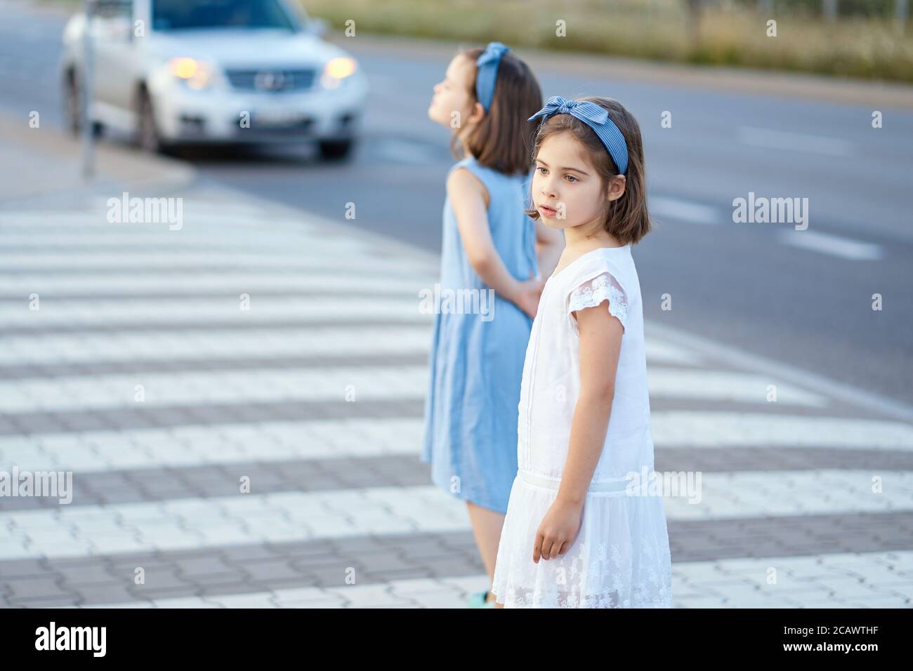 two cute little girls are walking along the city streets at sunset Stock Photo